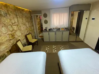 a bedroom with two beds and a stone wall at Petra Gateway Guest Room in Wadi Musa