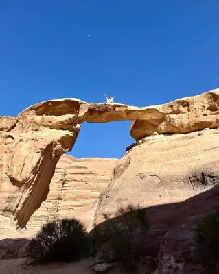 an arch in a rock formation in the desert at Wadi Rum Guide , Luxury Camp
