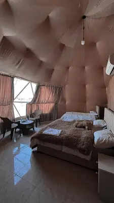 a bedroom with a large bed with a large wooden ceiling at Wadi Rum Guide , Luxury Camp