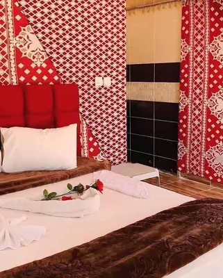 a room with two beds with red and white walls at Wadi Rum Guide , Luxury Camp