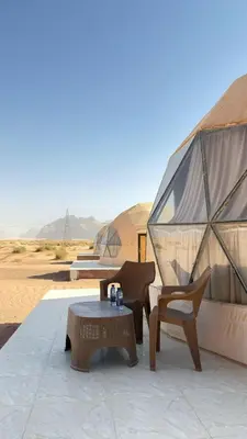 a patio with a table and chairs and tents in the desert at Wadi Rum Guide , Luxury Camp