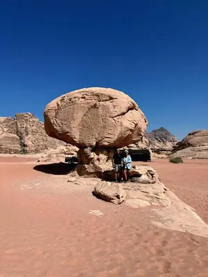two people sitting on a rock in the desert at Isabella Desert Camp & Tour in Wadi Rum