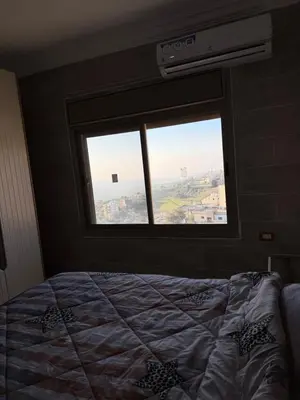 a bedroom with a bed and a large window at شقة للإيجار في راس منيف - عجلون in Ajloun