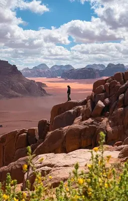 a person standing on the rocks looking out over the desert at Wadi Rum Mountains in Wadi Rum