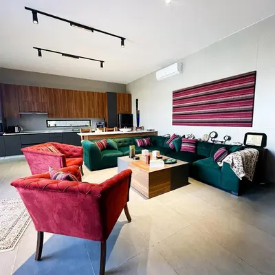 a living room with green couches and red chairs at Haifa Villa by Seahorse in Sowayma