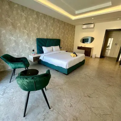 a bedroom with a bed and a green chair at Tonay I Villa by Seahorse in Al Rama