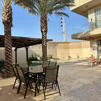a patio with a table and chairs and palm trees at Tonay I Villa by Seahorse in Al Rama