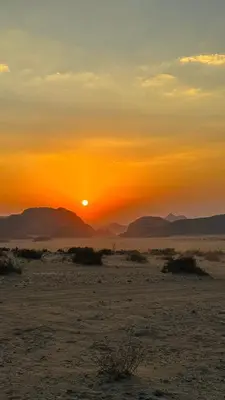 a sunset in the desert with the sun setting at Wadi Rum Starfield Retreat in Wadi Rum