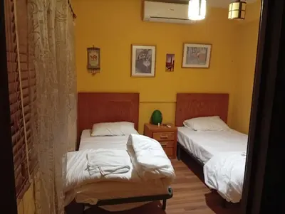 two beds in a room with yellow walls at Petra Neighbor Hostel in Petra