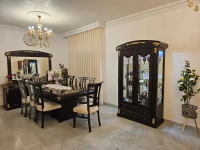a dining room with a table and chairs and a chandelier at شقة فاخرة في دير غبار in Amman