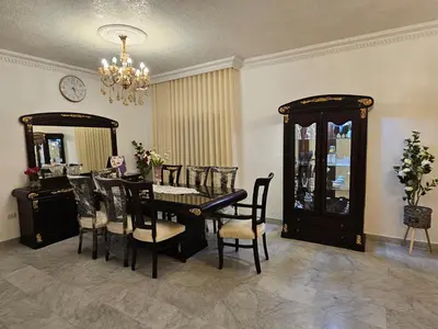 a dining room with a table and chairs and a chandelier at شقة فاخرة في دير غبار in Amman