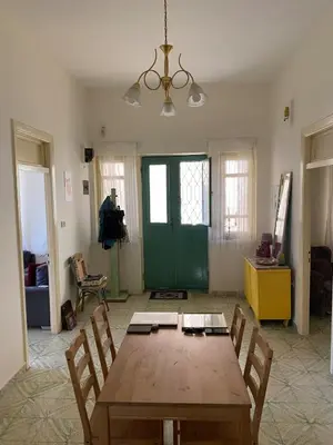 a dining room with a wooden table and a green door at Stylish 2BR Apartment, Walkable Jabal Al-Weibdeh in Amman