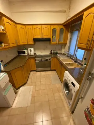 a kitchen with wooden cabinets and a washer and dryer at Stylish 2BR Apartment, Walkable Jabal Al-Weibdeh in Amman