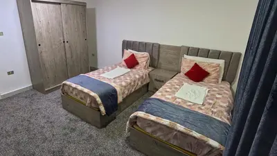 a bedroom with two beds and a couch with pillows at Masaya Al Deyar Apartments in Amman