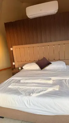 a bed with a white sheets and a light above it at sayd camp in Wadi Rum