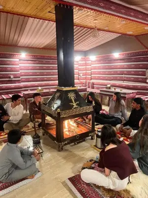 a group of people sitting around a fireplace at Star Desert Camp in Wadi Rum