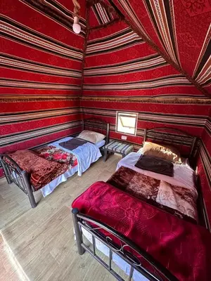 two beds in a room with red walls at Star Desert Camp in Wadi Rum