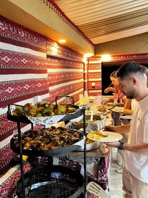 a man holding a plate of food at a buffet at Star Desert Camp in Wadi Rum