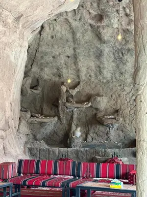 a room with a stone wall with red chairs at Imperial Rum Luxury Camp in Wadi Rum