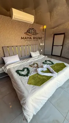 a bed with white sheets and green towels on it at MAYA RUM LUXURY CAMP & Jeep Tours in Disah
