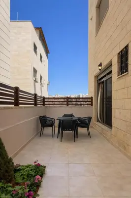 a patio with a table and chairs on a building at Der Ghbar 3BR - 2 Terraces, Scenic Views & BBQ in Amman