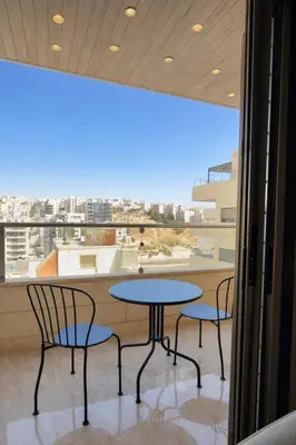 a table and chairs in a room with a large window at Der Ghbar 3BR - 2 Terraces, Scenic Views & BBQ in Amman