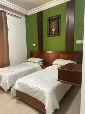 two beds in a room with green walls at Al Majd Hotel المجد للشقق الفندقية in Amman