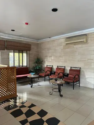 a waiting room with red chairs and tables at Al Majd Hotel المجد للشقق الفندقية in Amman