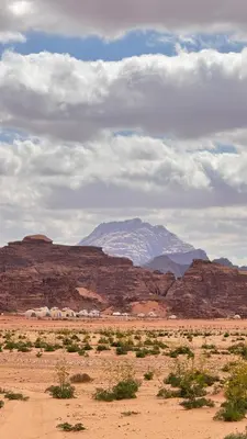 a desert with a snow covered mountain in the background at Red Moon Camp in Wadi Rum