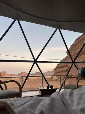 a bed in a tent with a view of the desert at Rina Luxury Camp in Disah