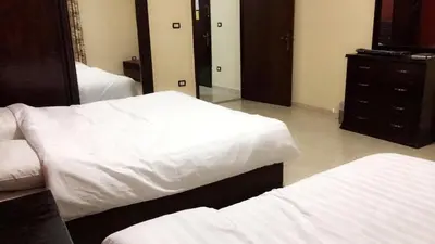 a bedroom with two white beds and a dresser at Al Tawheed Hotel Apartments in Amman