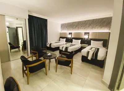 a hotel room with two beds and a table and chairs at Nishan Hotel in Amman
