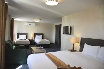 a hotel room with two beds and a chair at Olive Hotel Amman in Amman
