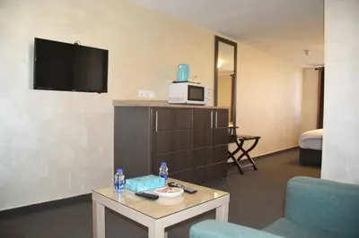 a hotel room with a tv and a couch and a table at Olive Hotel Amman in Amman
