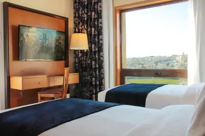 a hotel room with two beds and a desk and a window at Thousand Nights Hotel Amman - فندق ثاوزند نايتس عمان in Amman