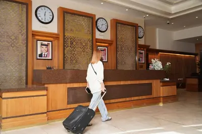 a woman walking through a lobby with a suitcase at Thousand Nights Hotel Amman - فندق ثاوزند نايتس عمان in Amman