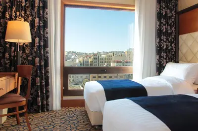 a hotel room with two beds and a large window at Thousand Nights Hotel Amman - فندق ثاوزند نايتس عمان in Amman