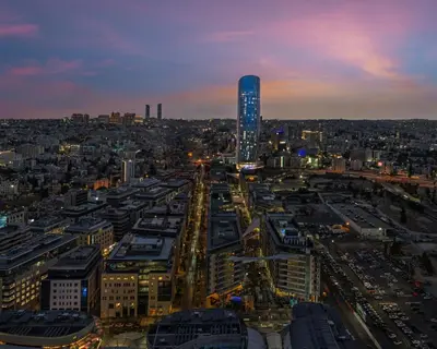 a city skyline at night with a tall building at Amman Rotana in Amman