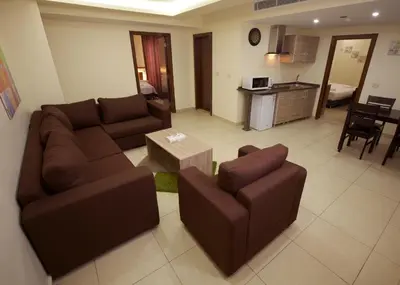 a living room with a couch and chairs and a kitchen at Lujain Hotel فندق النور واللجين in Amman