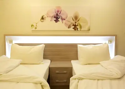 two beds in a hotel room with flowers on the wall at Lujain Hotel فندق النور واللجين in Amman