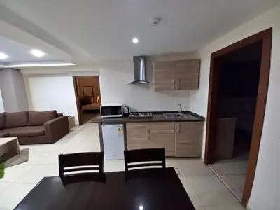 a kitchen and living room with a couch and a table at Lujain Hotel فندق النور واللجين in Amman