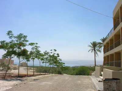 an empty street with palm trees and a building at Thara Real Estate in Sowayma