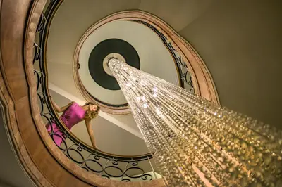 a woman walking down a spiral staircase with a chandelier at Grand Hyatt Amman Residences in Amman