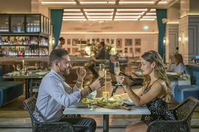 a man and woman sitting at a table with glasses of wine at Grand Hyatt Amman Residences in Amman