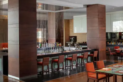 a bar in a restaurant with orange chairs and tables at Grand Hyatt Amman Residences in Amman