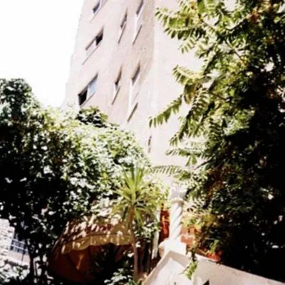 a tall building with trees in front of it at Farah Hotel in Amman