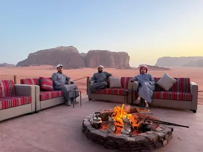 three men sitting around a fire in the desert at Wadi Rum Bedouin Camp in Wadi Rum