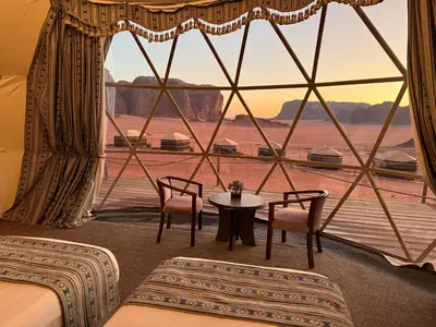 a room with two beds and a table and a large window at Wadi Rum Bedouin Camp in Wadi Rum