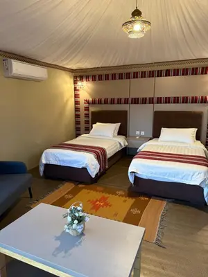two beds in a room with a table and a couch at Wadi Rum Bedouin Camp in Wadi Rum