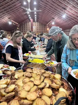a group of people standing around a table full of food at Khaled's Camp - Wadi Rum in Wadi Rum